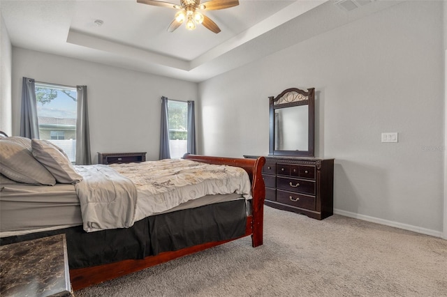 carpeted bedroom featuring ceiling fan and a tray ceiling