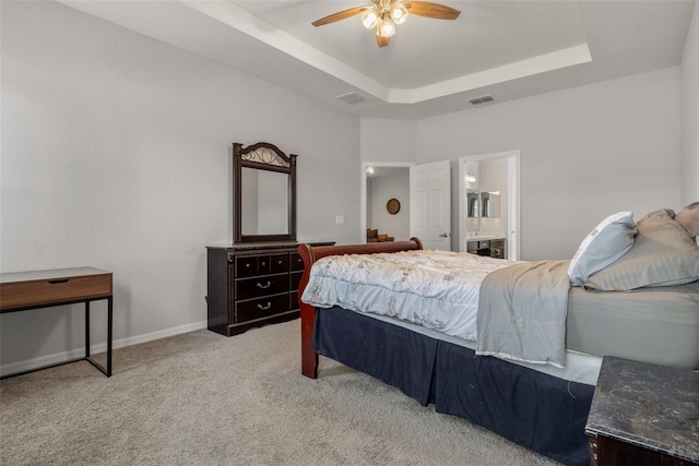 carpeted bedroom featuring ceiling fan, ensuite bath, and a tray ceiling