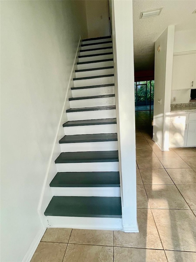 stairs featuring tile patterned flooring and a textured ceiling