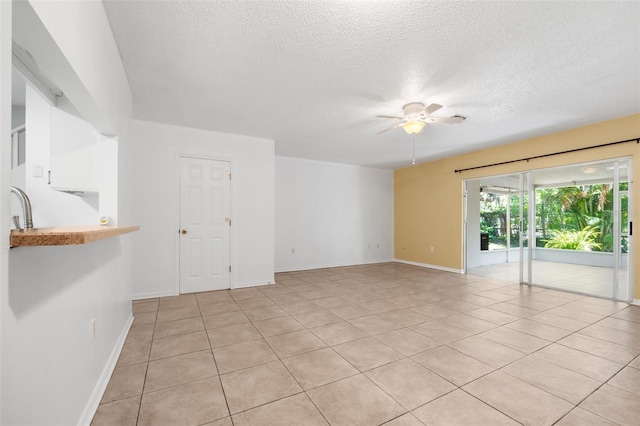 spare room with sink, light tile patterned floors, a textured ceiling, and ceiling fan