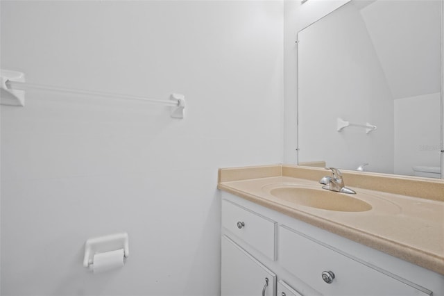 bathroom with lofted ceiling, vanity, and toilet