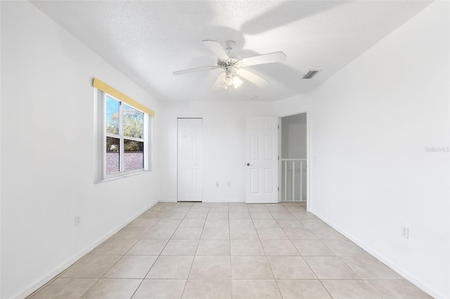 tiled spare room with a textured ceiling and ceiling fan