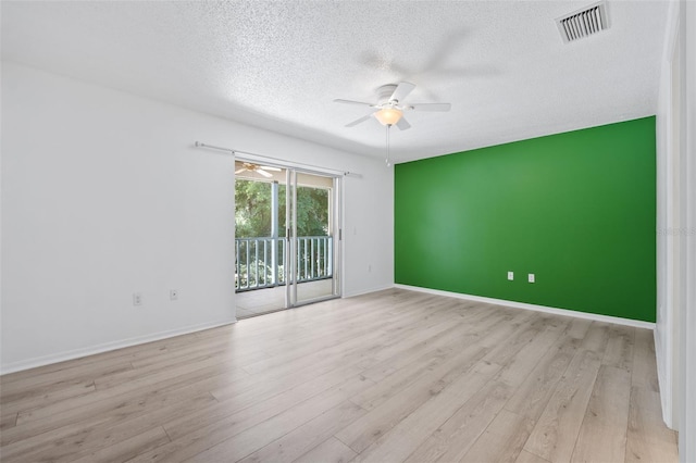 empty room featuring a textured ceiling, light hardwood / wood-style floors, and ceiling fan