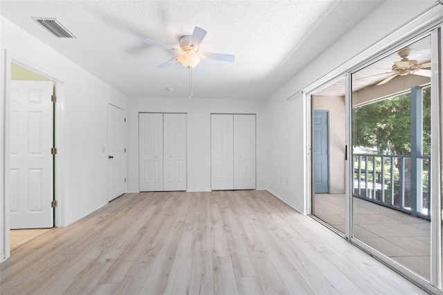 unfurnished bedroom with two closets, access to exterior, ceiling fan, light hardwood / wood-style floors, and a textured ceiling