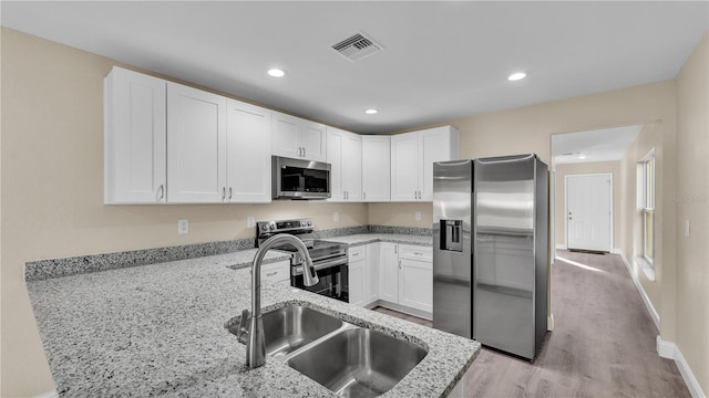 kitchen featuring white cabinetry, light stone countertops, stainless steel appliances, and sink