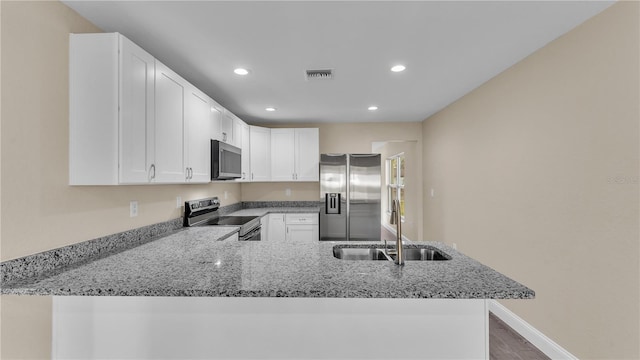 kitchen with light stone counters, sink, stainless steel appliances, and kitchen peninsula