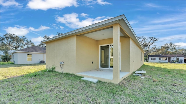 rear view of property featuring a yard, central AC unit, and a patio area