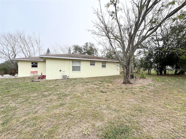 rear view of property with cooling unit and a lawn