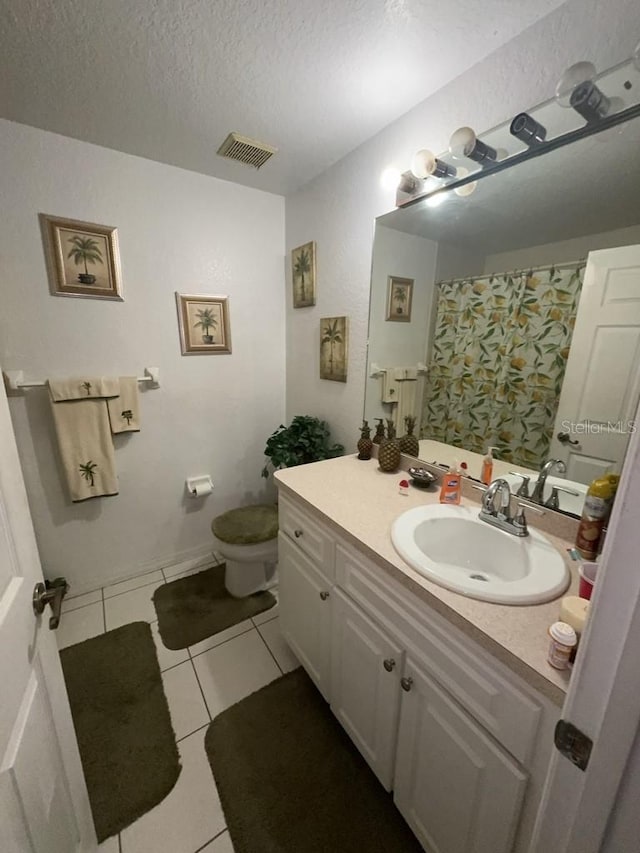 bathroom with tile patterned floors, toilet, a textured ceiling, and vanity