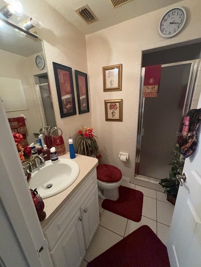 bathroom with tile patterned flooring, vanity, a shower with shower door, and toilet