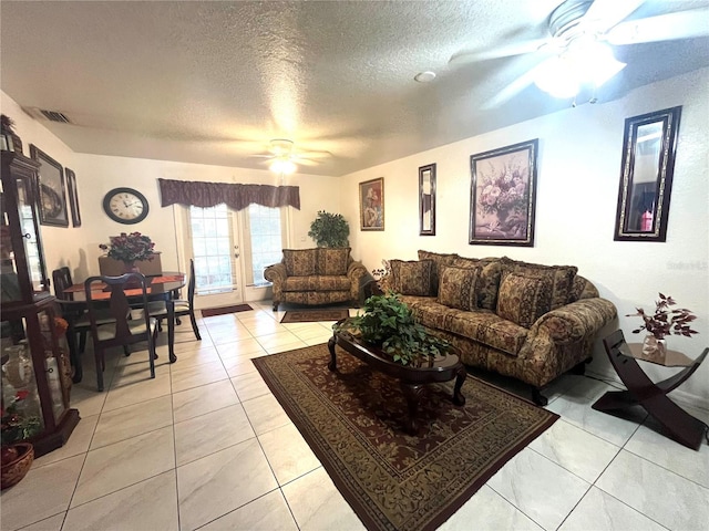 tiled living room with ceiling fan and a textured ceiling