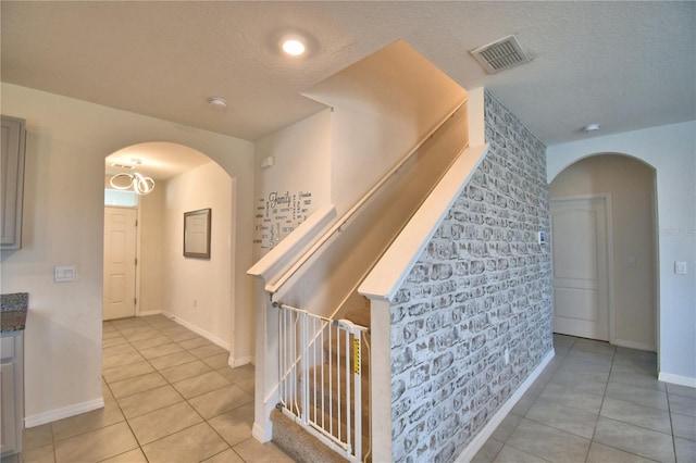 hallway featuring light tile patterned flooring and a textured ceiling