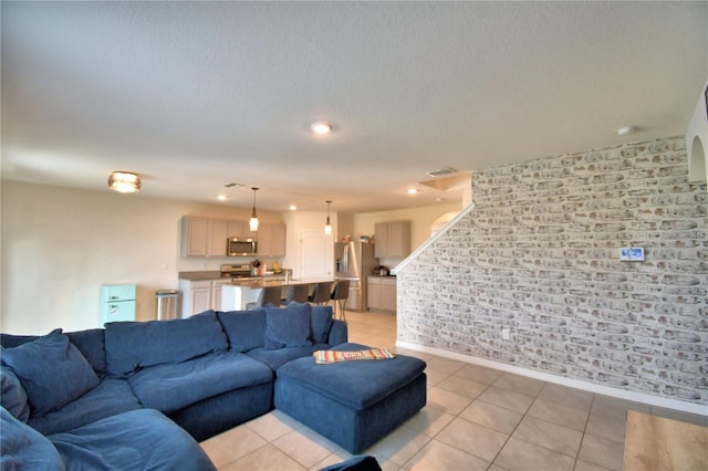 tiled living room featuring a textured ceiling and brick wall