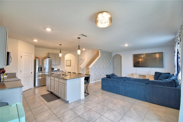 kitchen featuring sink, a breakfast bar area, appliances with stainless steel finishes, hanging light fixtures, and an island with sink