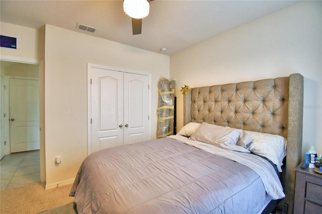 bedroom featuring light colored carpet, ceiling fan, and a closet