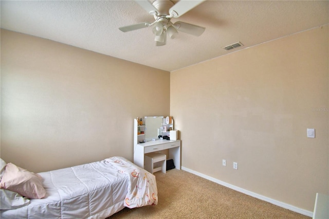 carpeted bedroom with ceiling fan and a textured ceiling