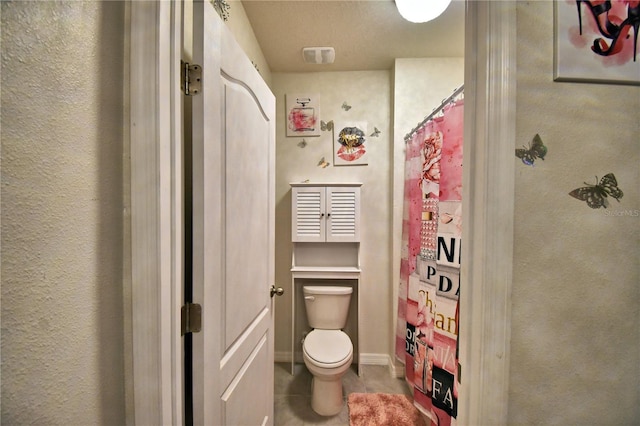 bathroom with tile patterned flooring, a shower with curtain, and toilet