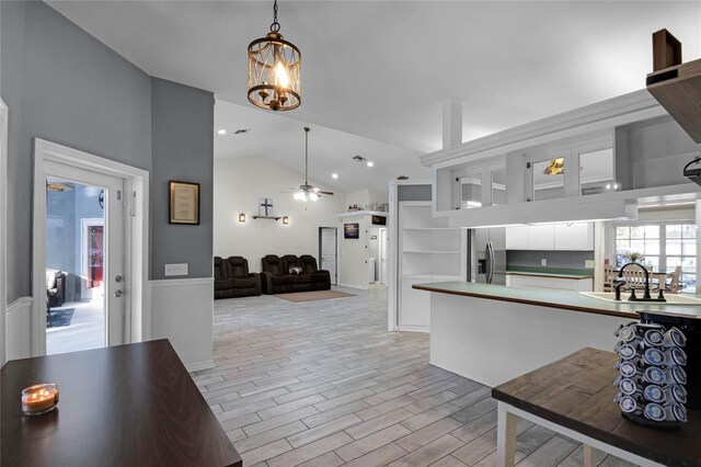 kitchen featuring vaulted ceiling, pendant lighting, white cabinets, stainless steel refrigerator with ice dispenser, and light wood-type flooring