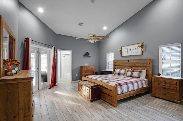 bedroom with multiple windows, high vaulted ceiling, light hardwood / wood-style floors, and french doors