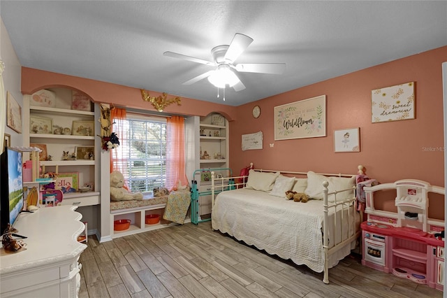 bedroom with ceiling fan, wood-type flooring, and a textured ceiling