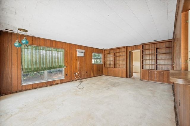 unfurnished living room with built in features, an AC wall unit, and wood walls