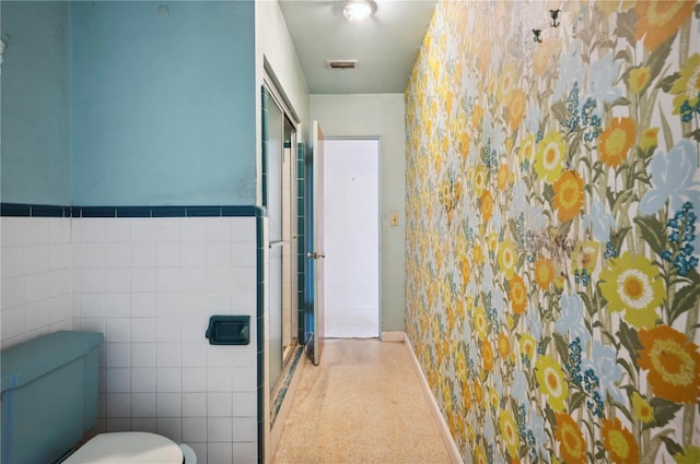 bathroom with toilet and tile walls