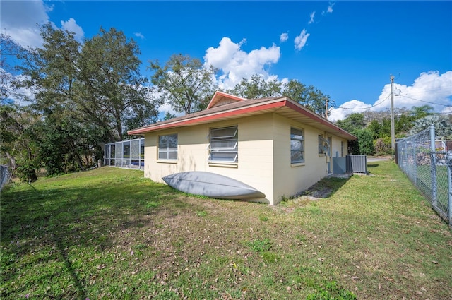 rear view of house featuring cooling unit and a yard