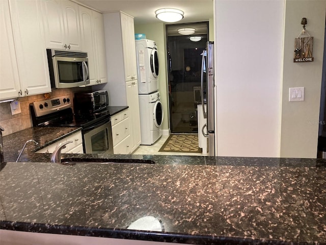 kitchen with white cabinetry, stacked washer / dryer, stainless steel appliances, and kitchen peninsula