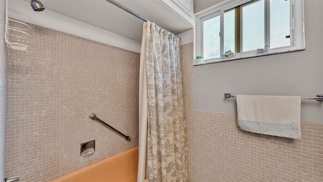 bathroom featuring shower / bath combination with curtain and tile walls