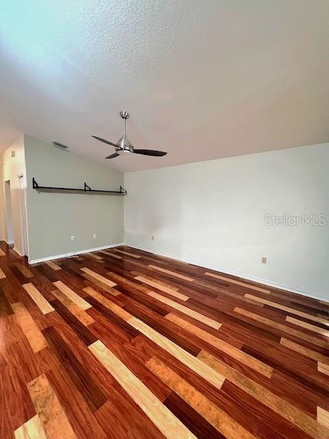 unfurnished room featuring hardwood / wood-style flooring, ceiling fan, vaulted ceiling, and a textured ceiling