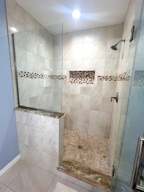 bathroom featuring tile patterned flooring and tiled shower