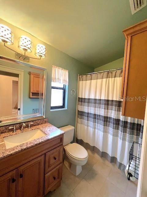 bathroom featuring vanity, vaulted ceiling, and toilet