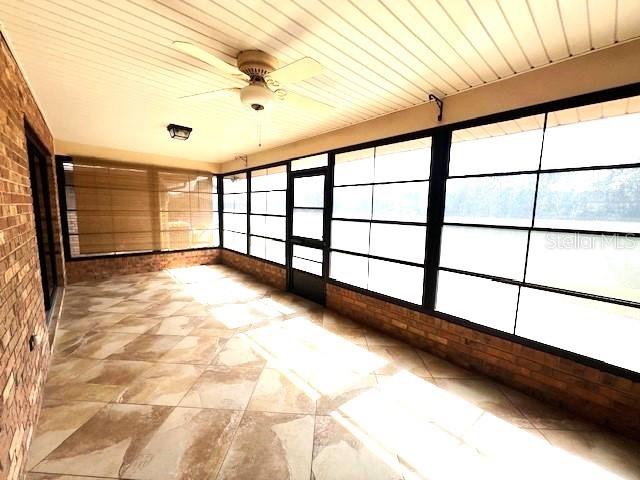 unfurnished sunroom featuring ceiling fan