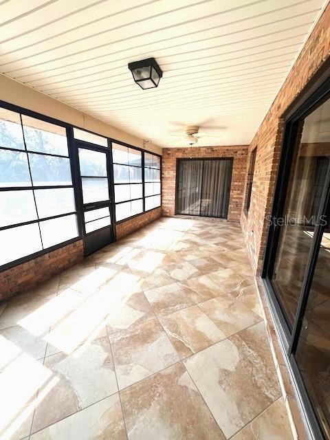 unfurnished sunroom featuring a healthy amount of sunlight and ceiling fan