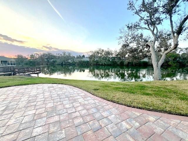 patio terrace at dusk with a water view and a lawn