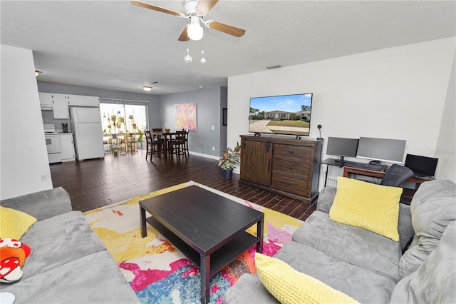 living room featuring ceiling fan, dark hardwood / wood-style floors, and a textured ceiling