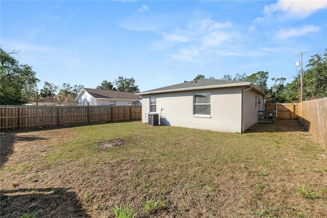 rear view of property with central AC unit and a lawn