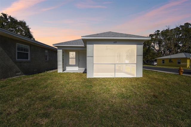 back house at dusk with a lawn