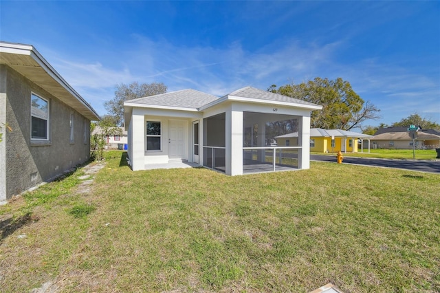 back of house featuring a sunroom and a lawn