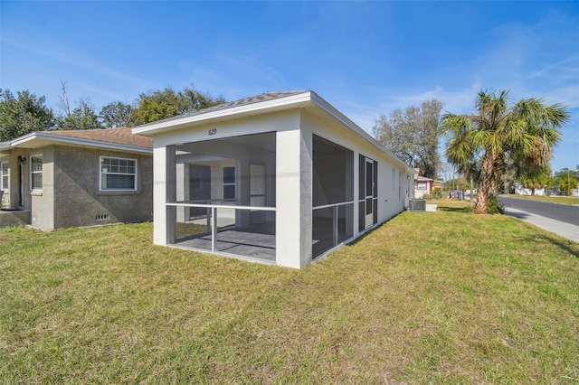 back of property with a sunroom, central AC unit, and a lawn