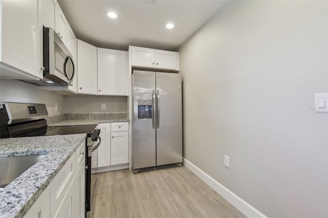 kitchen featuring white cabinetry, stainless steel appliances, light stone counters, and light wood-type flooring