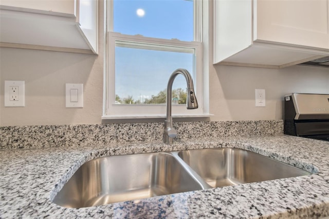 details featuring white cabinetry, sink, and light stone countertops