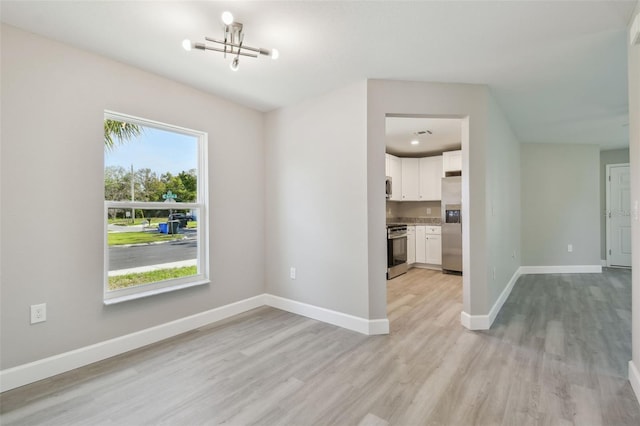 unfurnished dining area with light hardwood / wood-style flooring and a chandelier