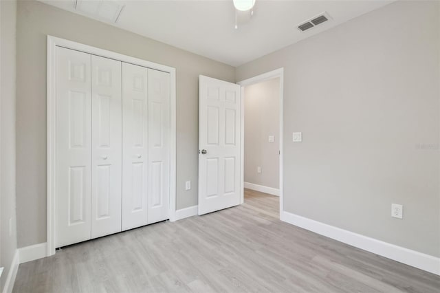 unfurnished bedroom featuring ceiling fan, a closet, and light wood-type flooring