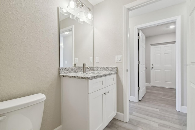 bathroom featuring vanity, wood-type flooring, and toilet