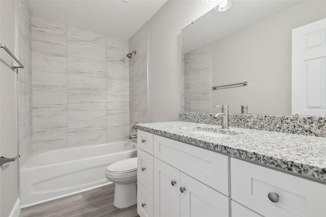 full bathroom featuring hardwood / wood-style flooring, tiled shower / bath, vanity, and toilet