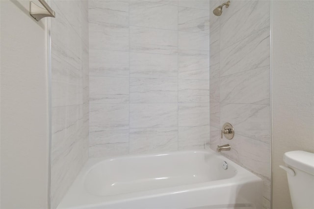 bathroom with tiled shower / bath combo and toilet