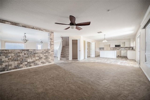 unfurnished living room featuring ceiling fan, light colored carpet, and a textured ceiling