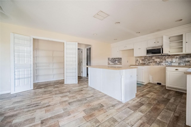 kitchen featuring tasteful backsplash, light hardwood / wood-style floors, white cabinets, and a kitchen island