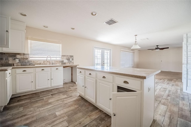 kitchen with hanging light fixtures, sink, white cabinets, and a kitchen island